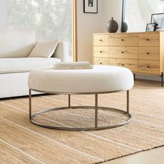 a living room scene with focus on the ottoman and coffee table in the foreground