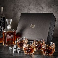 four whiskey glasses sitting in front of a bottle