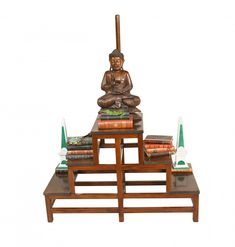 a buddha statue sitting on top of a wooden table with books and other items around it