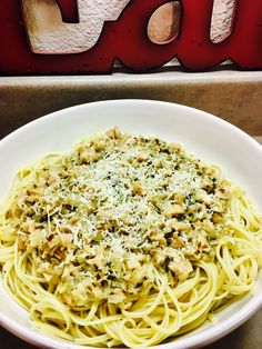 a white bowl filled with pasta and topped with parmesan cheese