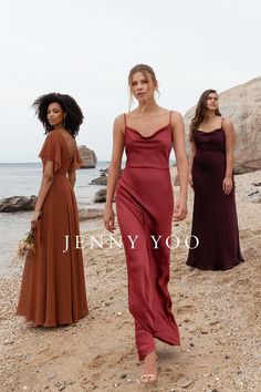 three women in dresses walking on the beach