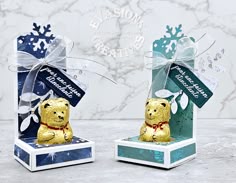 two small boxes that have some kind of gold bear in them on top of each other