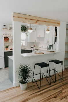 a kitchen with two stools next to a counter top and a potted plant