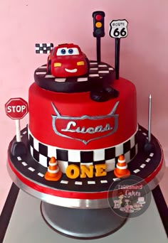 a red cake with cars on it sitting on top of a table next to a stop sign