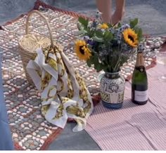 a table topped with bottles of wine and flowers next to a basket filled with sunflowers