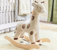 a stuffed giraffe sitting on top of a wooden rocking toy in a nursery