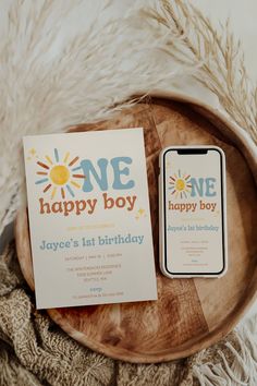 two birthday cards sitting on top of a wooden plate next to a cell phone with the number one happy boy