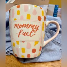 a coffee mug with the words mommy fuel printed on it sitting on a wooden table