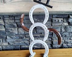 a white and brown horse shoe holder on top of a wooden table next to a brick wall