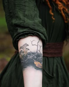 a woman wearing a green dress with tattoos on her arm