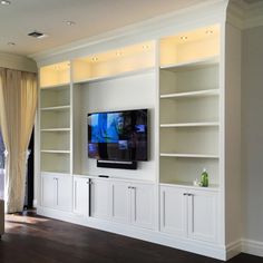 a flat screen tv sitting on top of a white bookcase in a living room