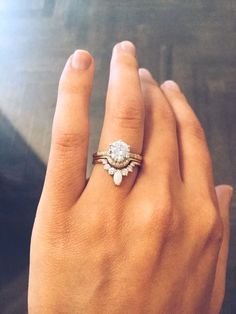 a woman's hand with a diamond ring on top of her finger and the other hand holding an engagement ring