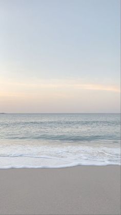 an empty beach with the ocean in the background