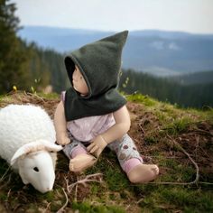 a doll sitting on the ground next to a sheep