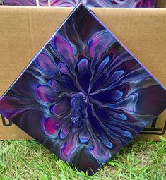 a purple and blue glass plate sitting on top of a cardboard box in the grass