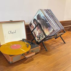 an old record player sitting on top of a wooden floor next to a suitcase with the cover open