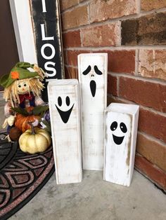 three wooden blocks with faces painted on them sitting in front of a brick wall and pumpkins