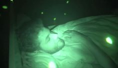 a man laying in bed with his head on the pillow while looking at something green