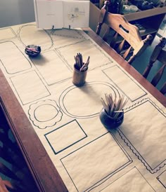 the table is set up with paper cut out to look like a plan for a house