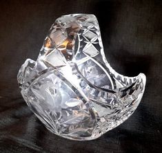 a clear glass bowl sitting on top of a black tableclothed surface with light shining through it