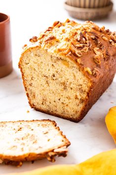 a loaf of bread sitting on top of a counter next to sliced bananas and other fruit