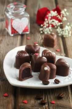 several pieces of chocolate on a white plate with red and white flowers in the background