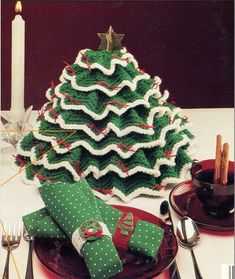 a crocheted christmas tree sitting on top of a table next to silverware