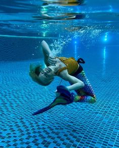 a woman swimming underwater in a pool