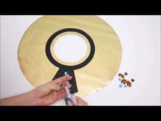 a person is making a paper plate with scissors and beads on it that has a gold circle in the middle