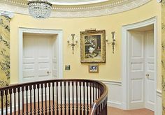 a spiral staircase in an ornately decorated room with paintings on the walls and chandelier