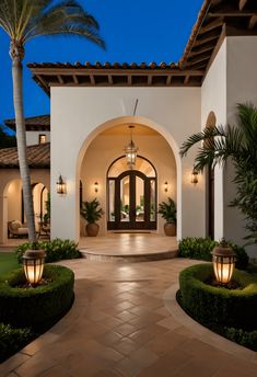 an entrance to a home with potted plants and lights on the walkway at night