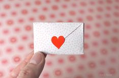 a person holding up a piece of paper with a heart on it