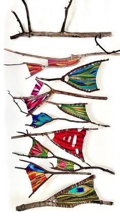 several different colored flags hanging from branches on a wall in front of a white background