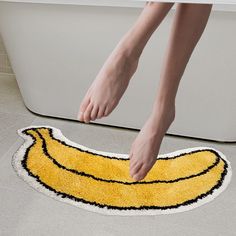 a person standing over a bathtub with a yellow rug on the floor next to it