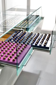 there are many chocolates on display in the glass case, and one is pink