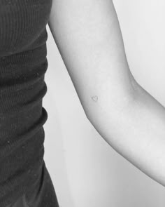 a woman's arm with a small dot tattoo on it