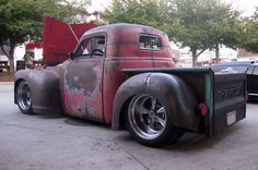 an old red truck is parked on the street