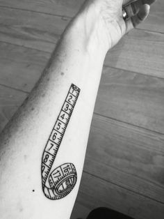 a black and white photo of a person's arm with a measuring tape tattoo on it