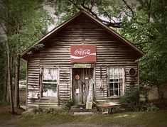 an old wooden building with a coca - cola sign on it's front door