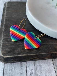 two colorful heart shaped wooden earrings sitting on top of a table next to a plate