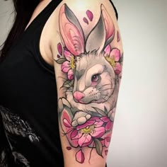 a woman's arm with a rabbit and flowers tattoo on the left side of her body