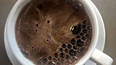 a close up of a cup of coffee on a saucer with water droplets in it