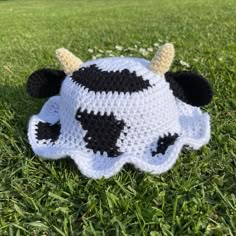 a crocheted cow hat laying in the grass