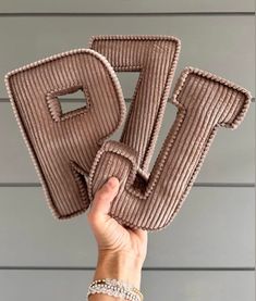 a hand holding up two pieces of fabric with the letter p on it's side