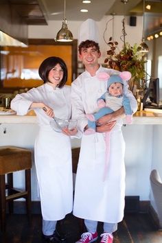 a man and woman in chef outfits holding a baby