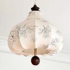 a white lamp hanging from a ceiling with flowers on it