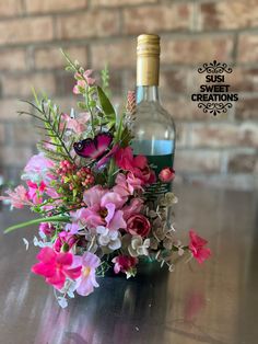 a bottle of wine sitting on top of a table next to a bouquet of flowers