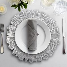 a place setting with silverware and white flowers on the table, along with napkins