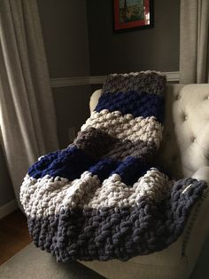 a crocheted blanket sitting on top of a white chair next to a window