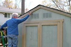 an older man is painting the side of a shed